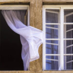 Two wooden windows in concrete wall and curtain